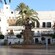 A fountain at the center of a Spanish apartment building courtyard has porcelain tile and palm trees